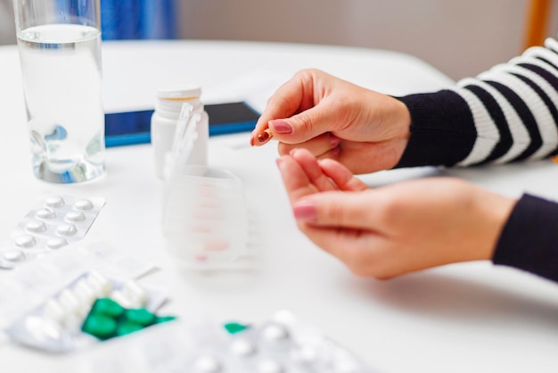 Donna che mette a mano le pillole in un organizzatore di pillole aperto o in una scatola di pillole di plastica