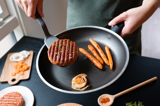 Donna che mette carne vegana a base vegetale da una padella su un piatto per un pranzo a base di cibo sano senza carne