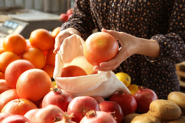 Donna che mette l'arancia nella borsa ecologica di cotone al primo piano del mercato all'ingrosso Vita senza plastica