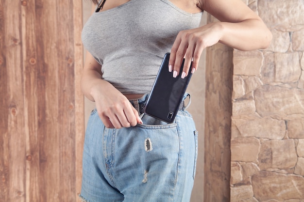 Donna che mette smartphone in tasca dei jeans.