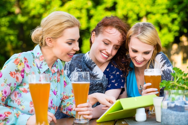 Donna che mostra gli amici tocco pad nel giardino della birra