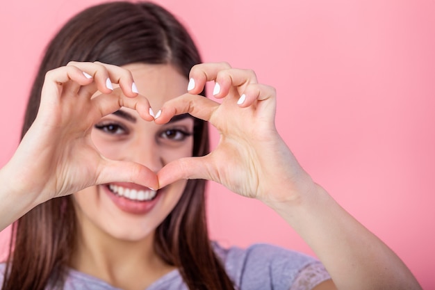 Donna che mostra il gesto del cuore, guardando la fotocamera