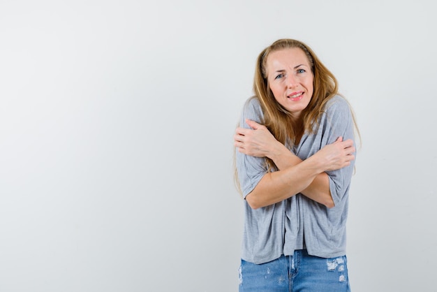 Donna che mostra il gesto della mano fredda con le braccia incrociate sul seno su sfondo bianco