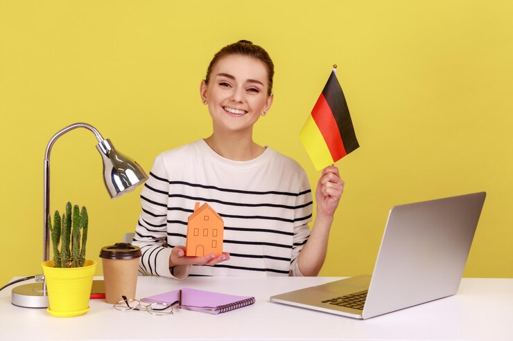 Donna che mostra la bandiera della germania seduta sul posto di lavoro con l'acquisto di una casa di carta