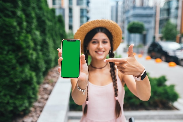 Donna che mostra smartphone moderno con schermo verde per la sostituzione