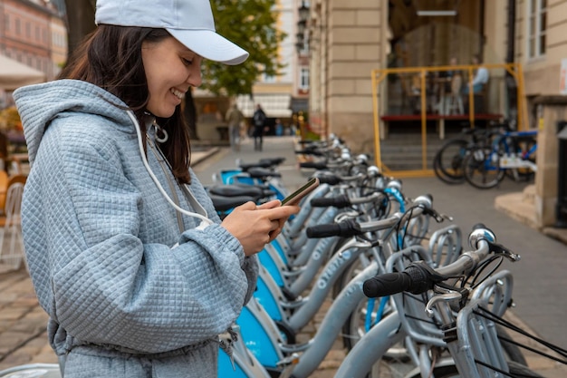 Donna che noleggia bici da città con app mobile moderno trasporto ecologico