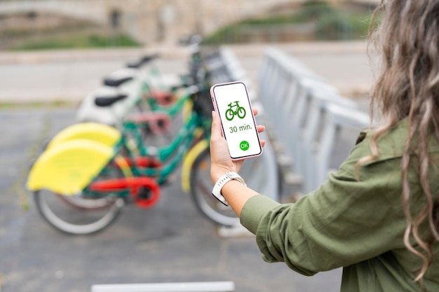 Donna che noleggia una bicicletta con il suo smartphone in città