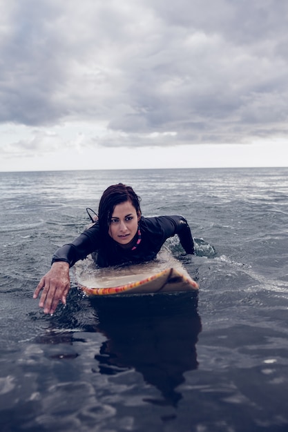 Donna che nuota sopra la tavola da surf in acqua