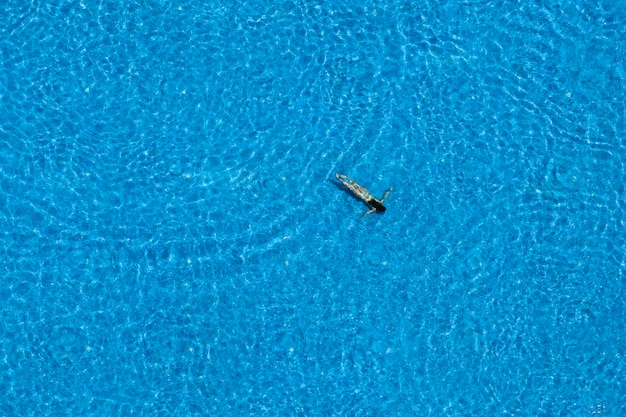 Donna che nuota sott'acqua in una piscina, vista dall'alto. Viaggio estivo e concetto di vacanza