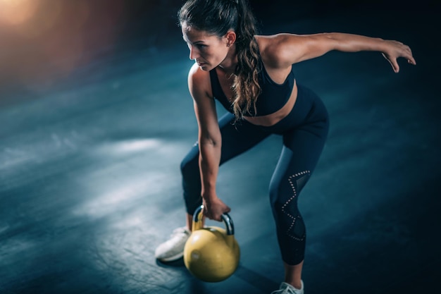 Donna che oscilla Kettlebell in palestra