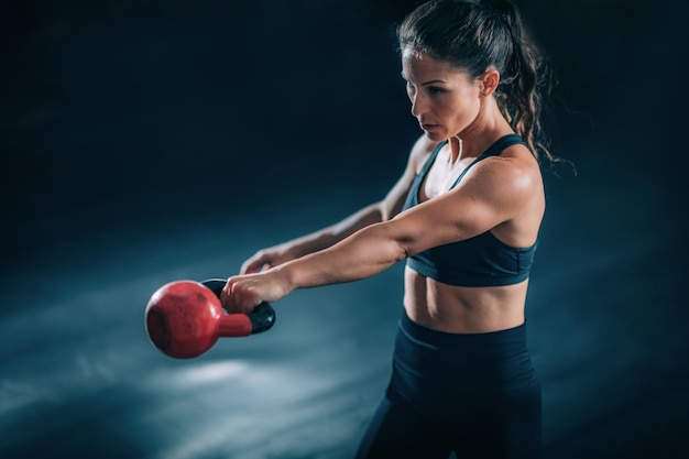 Donna che oscilla Kettlebell in palestra