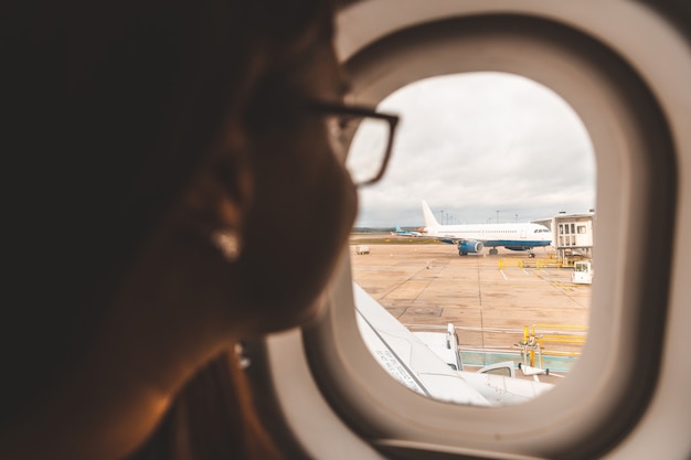 Donna che osserva dalla finestra dell&#39;aeroplano all&#39;aeroporto