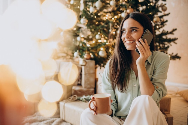 Donna che parla al telefono vicino all'albero di Natale