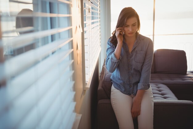 Donna che parla su smart phone mentre è seduto sul divano