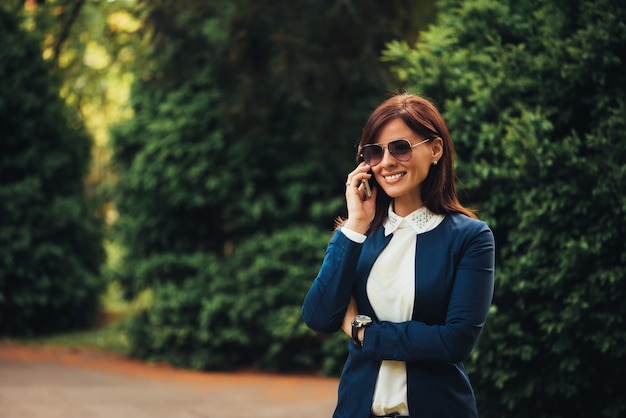 Donna che parla sul cellulare mentre esplora il parco della città