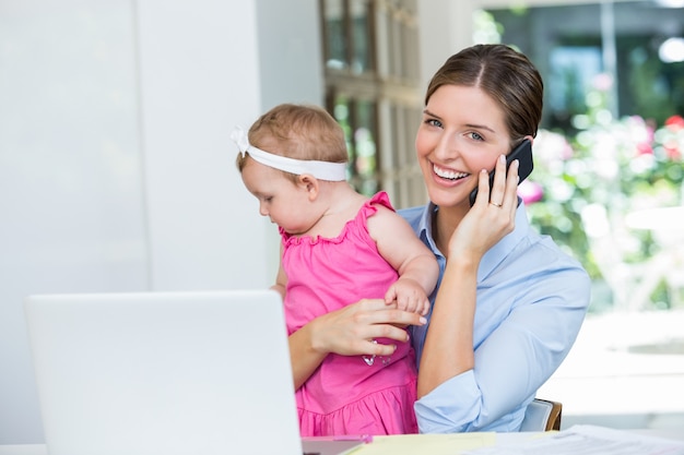 Donna che parla sul telefono cellulare mentre era seduto con la bambina