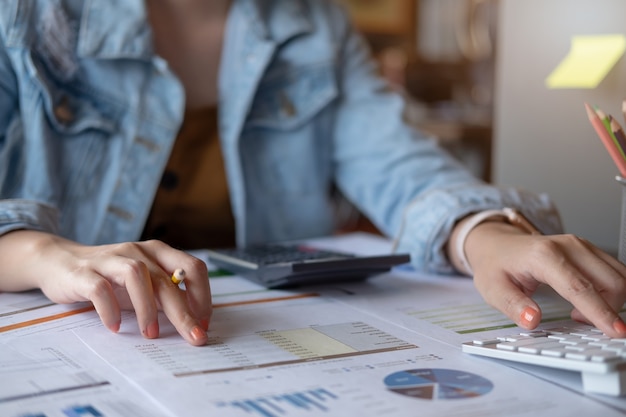 Donna che per mezzo del calcolatore mentre lavorando per i documenti finanziari