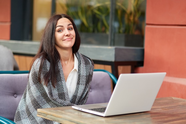 Donna che per mezzo del computer portatile al caffè