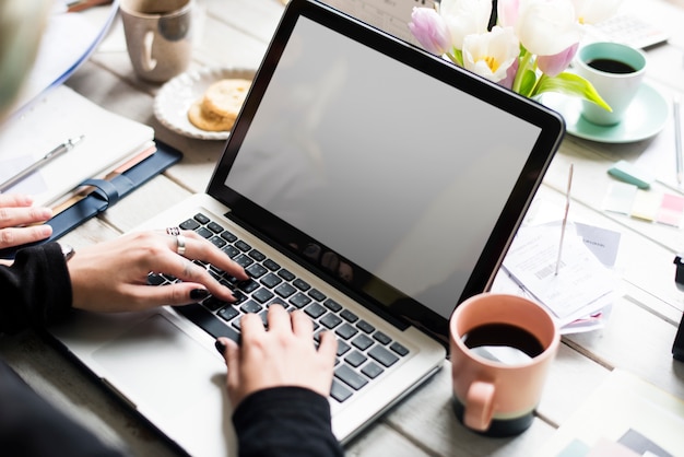 Donna che per mezzo del computer portatile con il fiore decorato