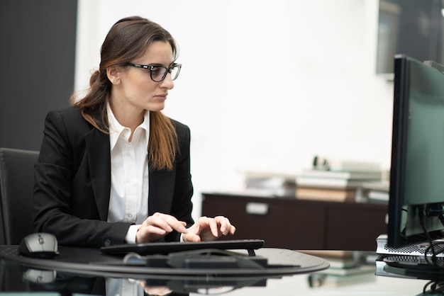 Donna che per mezzo del suo computer sul lavoro