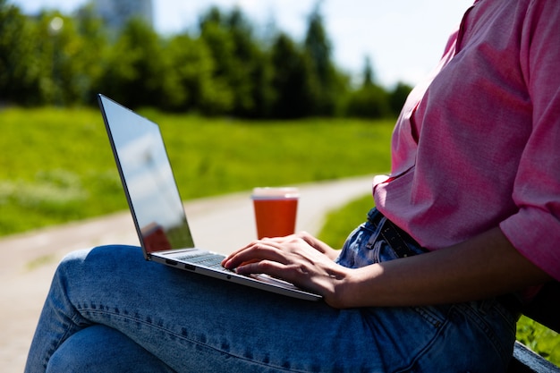 donna che per mezzo di un computer portatile mentre era seduto su una panchina