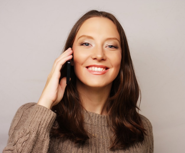 Donna che per mezzo di un telefono cellulare isolato su bianco