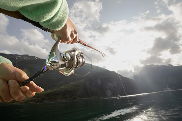 Donna che pesca con la canna da pesca spinning in Norvegia La pesca in Norvegia è un modo per abbracciare lo stile di vita locale Innumerevoli laghi e fiumi e una vasta costa significa opportunità eccezionali