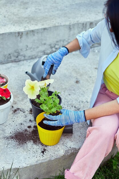 Donna che pianta petunia surfinia fiori vaso concetto di giardinaggio a casa