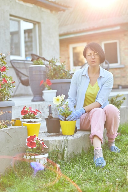 Donna che pianta petunia surfinia fiori vaso concetto di giardinaggio a casa