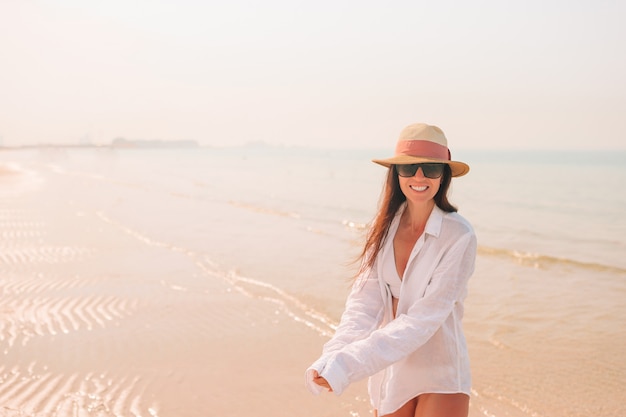 Donna che pone sulla spiaggia godendo le vacanze estive guardando il mare