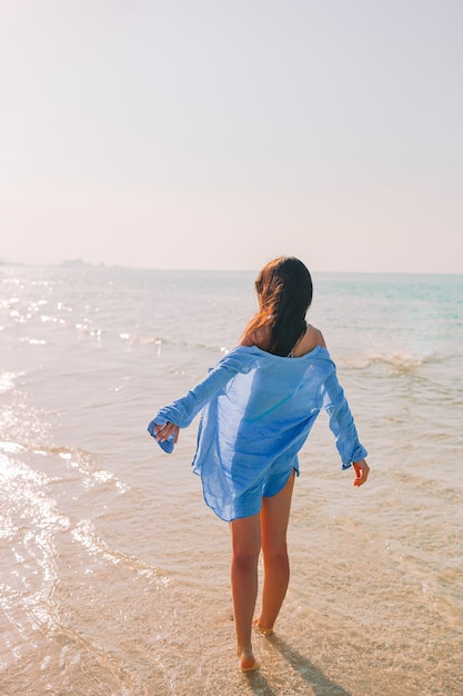 Donna che pone sulla spiaggia godendo le vacanze estive guardando il mare