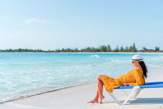 Donna che pone sulla spiaggia godendo le vacanze estive guardando il mare