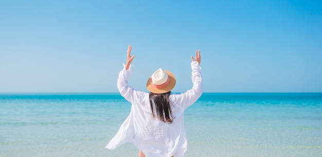 Donna che pone sulla spiaggia godendo le vacanze estive guardando il mare