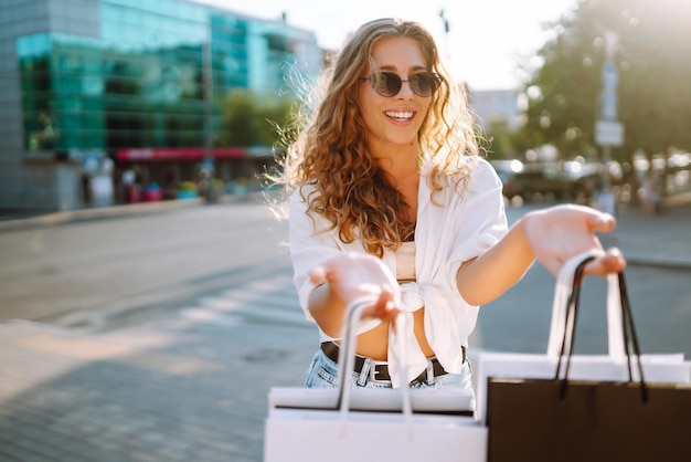 Donna che porta delle borse della spesa che cammina per la strada della città Black Friday Acquisti concetto di stile di vita