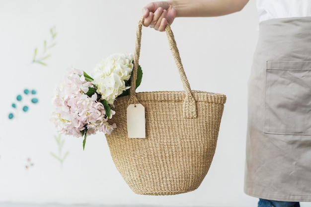 Donna che porta le ortensie in un sacchetto di vimini