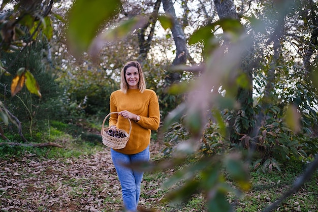 Donna che porta un cesto di vimini con tante castagne raccolte in un pomeriggio d'autunno