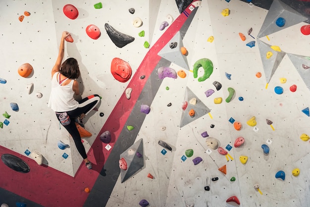 Donna che pratica arrampicata su parete artificiale per interni. Stile di vita attivo e concetto di bouldering.