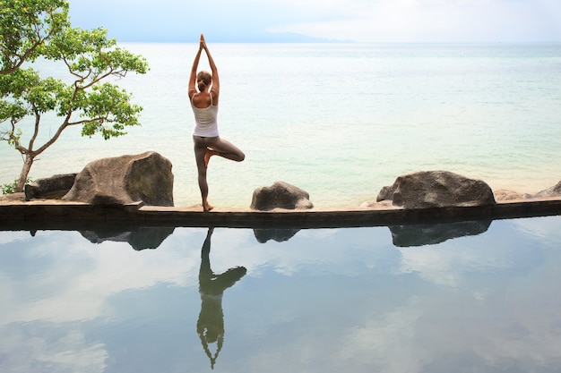 Donna che pratica o fa meditazione mattutina Yoga in natura in spiaggia