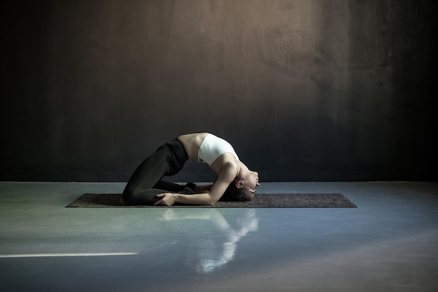 Donna che pratica yoga facendo esercizio di piccione posa di Kapotasana