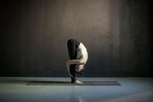 Donna che pratica yoga facendo esercizio uttanasana dalla testa alle ginocchia