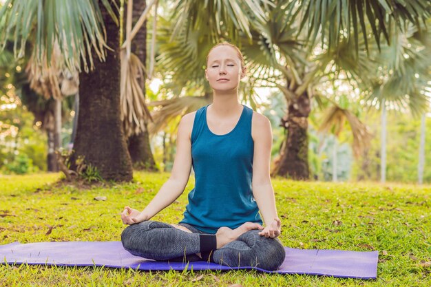 Donna che pratica yoga in un parco tropicale.