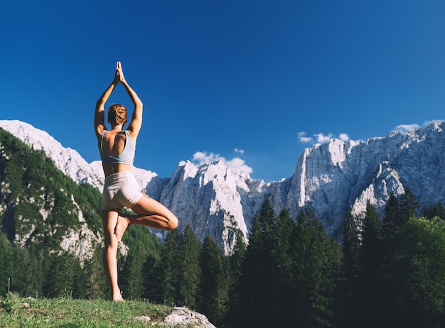 Donna che pratica yoga sulla natura Giovane donna che fa yoga in montagna