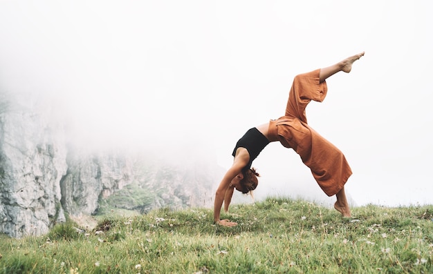 Donna che pratica yoga sulla natura Giovane donna che fa yoga in montagna