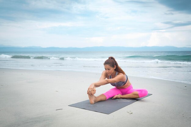 Donna che praticano yoga sulla spiaggia