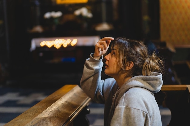 Donna che prega in ginocchio in un antico tempio cattolico a Dio Mani piegate nel concetto di preghiera per la fede spiritualità e religione Concetto di pace speranza sogni