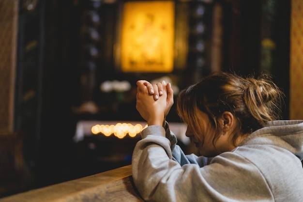 Donna che prega in ginocchio in un antico tempio cattolico a Dio Mani piegate nel concetto di preghiera per la fede spiritualità e religione Concetto di pace speranza sogni