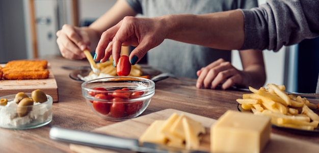 Donna che prende il pomodoro ciliegia da un piatto sulla tavola