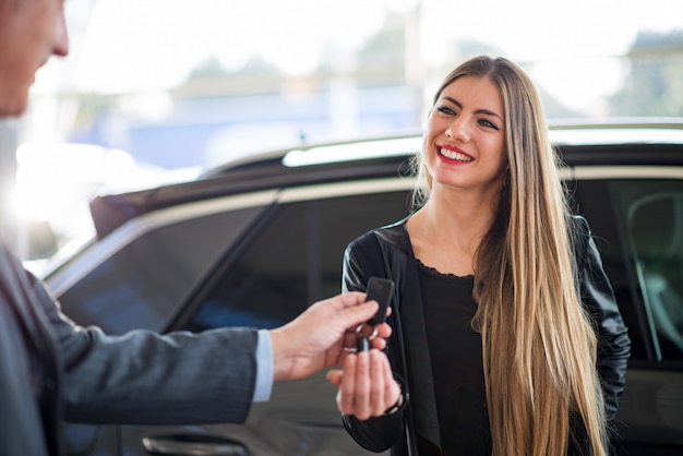 Donna che prende le chiavi della sua auto in uno showroom