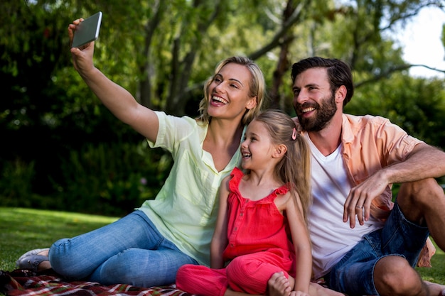 Donna che prende selfie con il marito e la figlia all'iarda