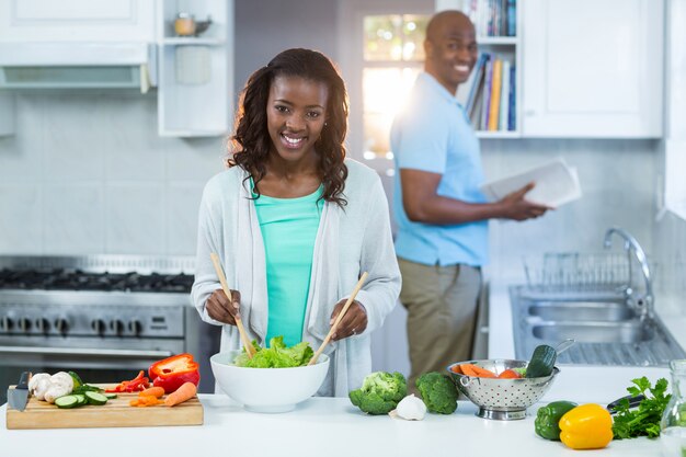 Donna che prepara cibo mentre uomo in piedi